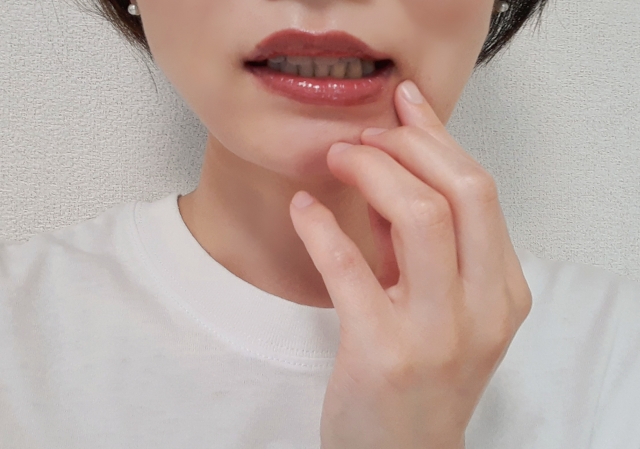 口元に手を当てている女性の写真