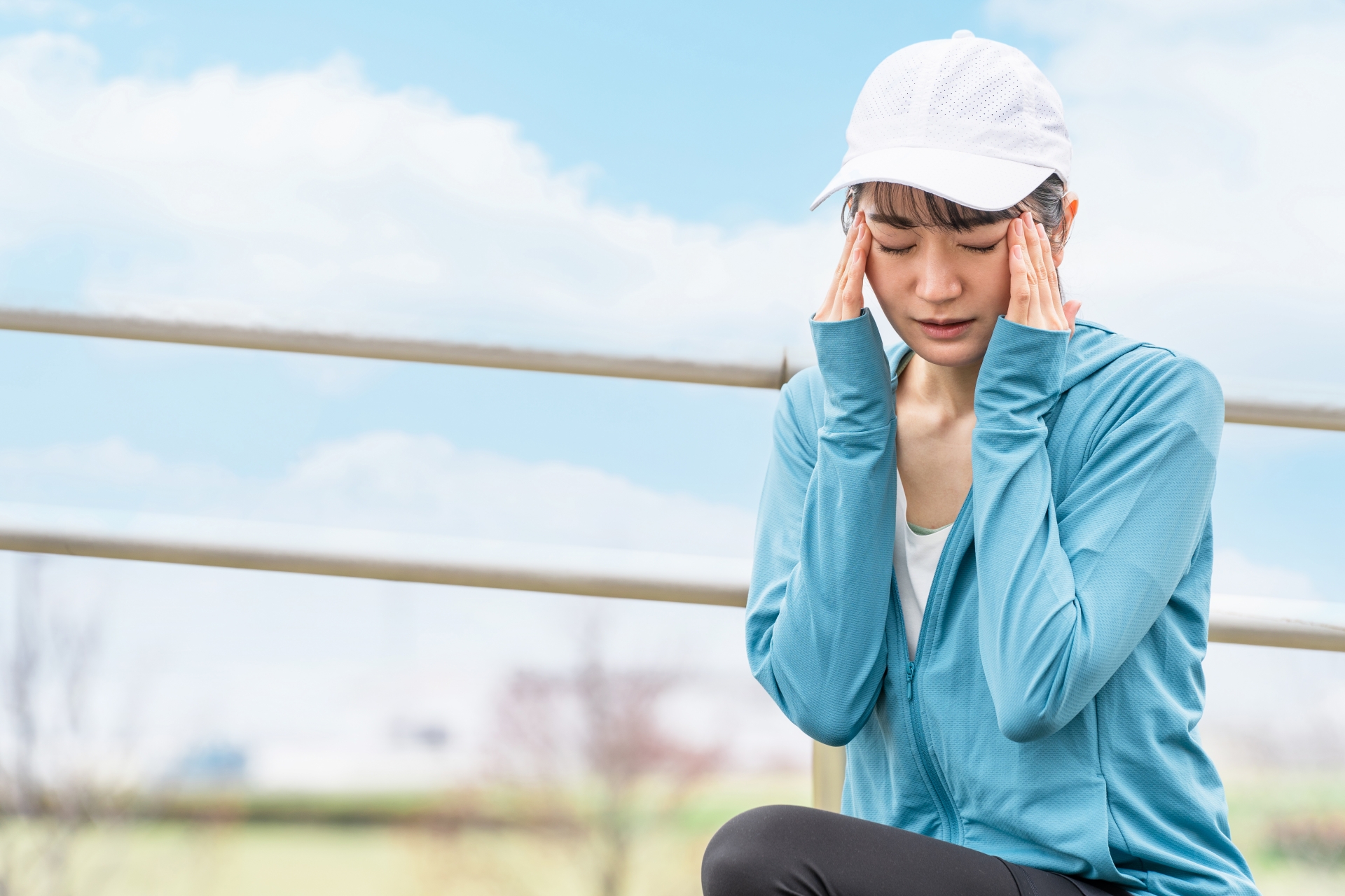 夏の日差しの中で体調が悪くうずくまっている女性