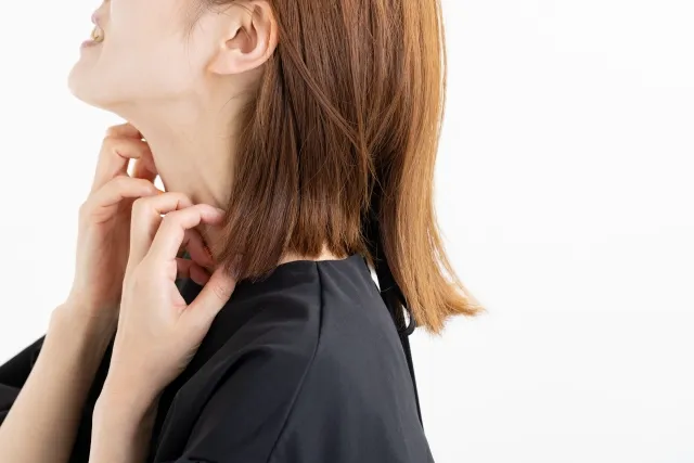 あせもで首を搔きむしる女性