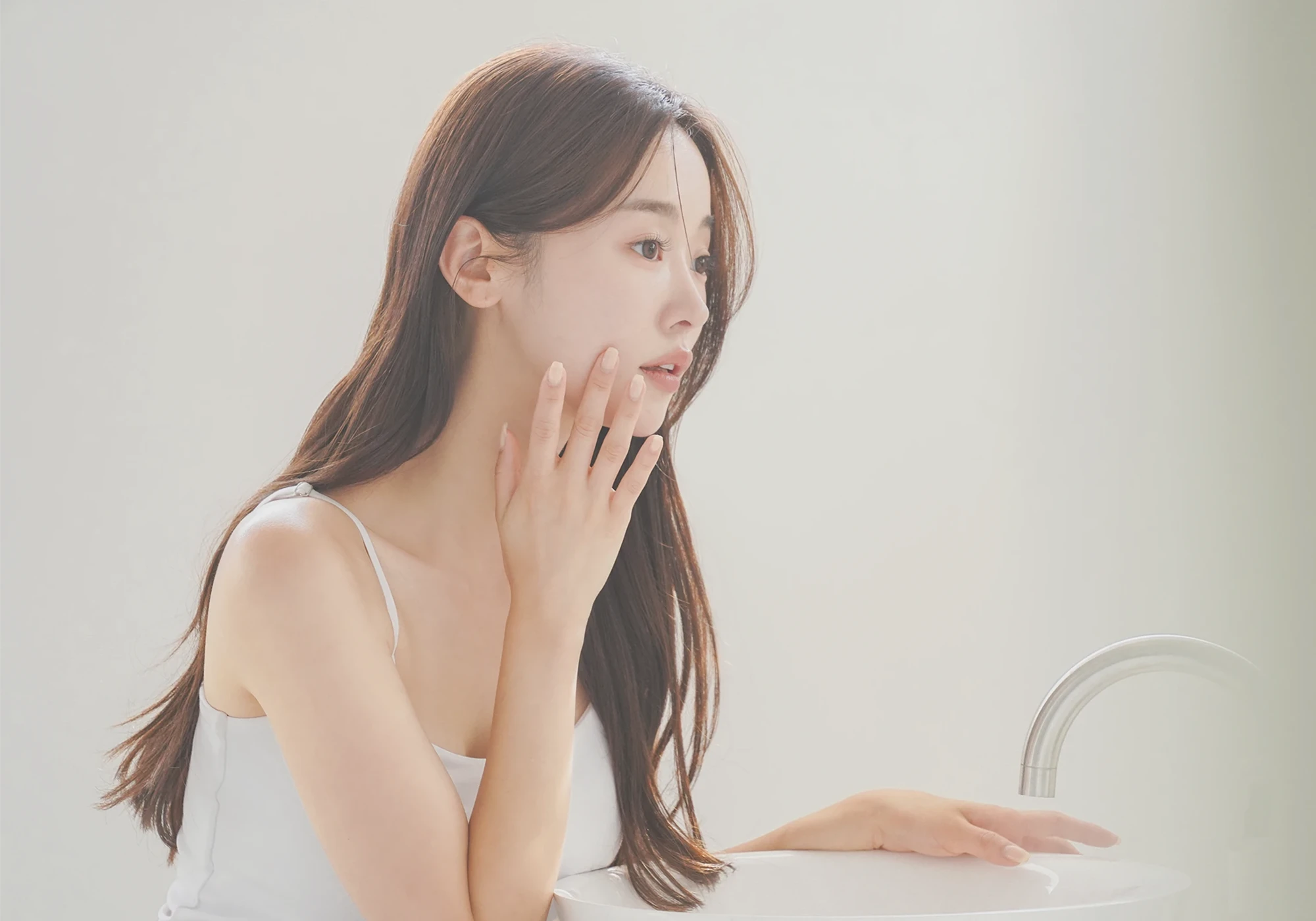 鏡を見てフェイスラインを気にする女性