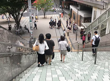 改札を背に目の前の大きな広場と階段を下におりる様子