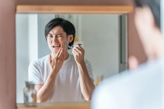 カミソリでひげをそっていて、痛がっている男性