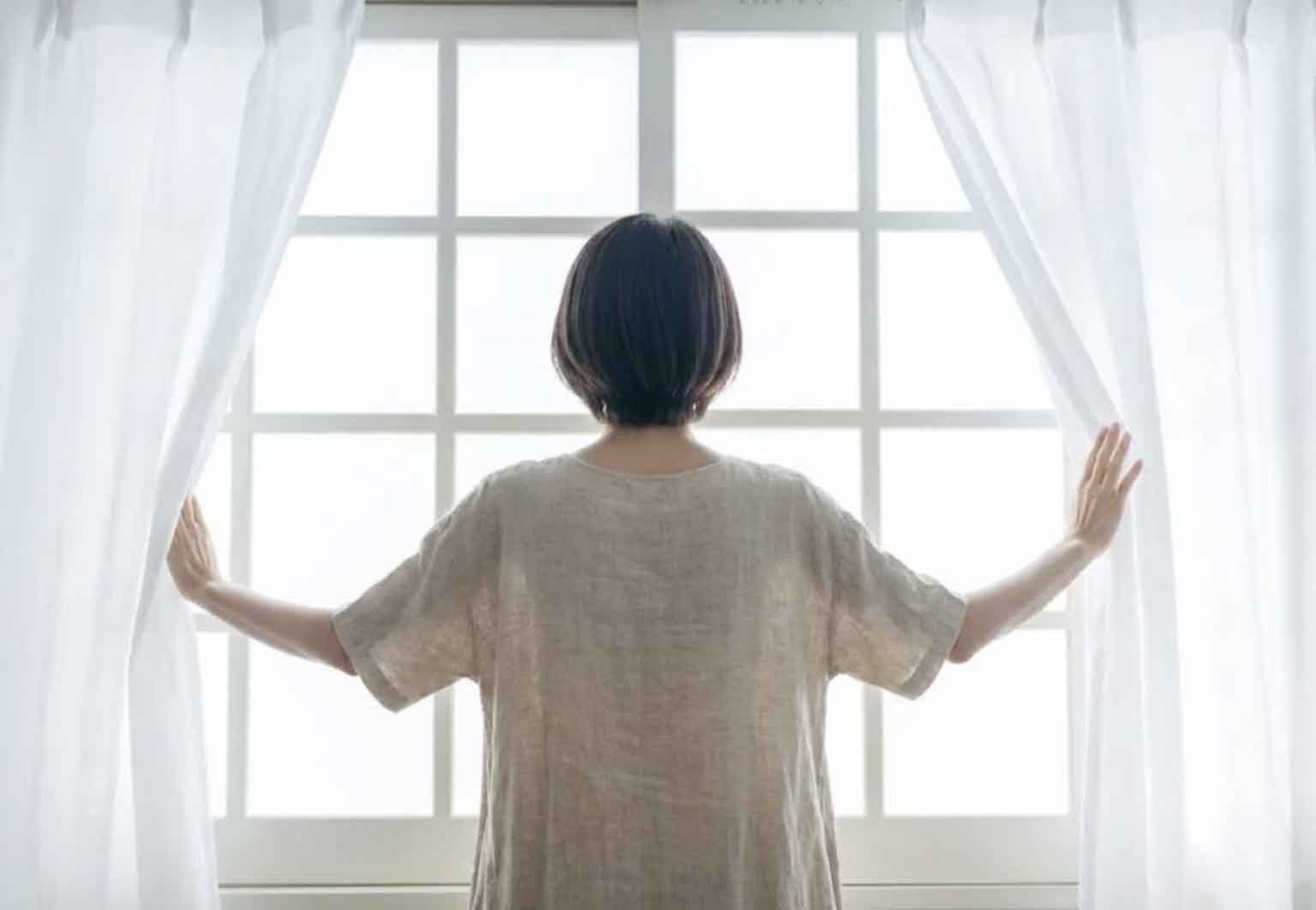 女性がカーテンを開けている様子