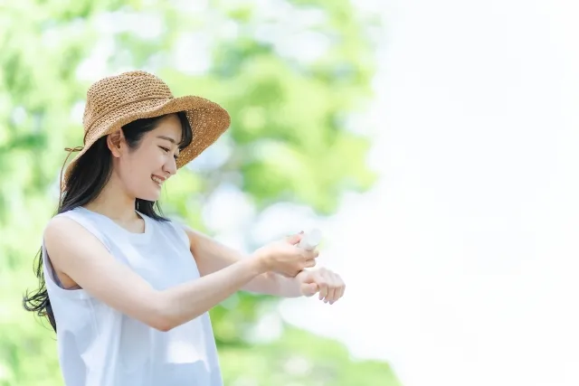 屋外でのレジャー前に虫よけスプレーを塗布して予防する女性