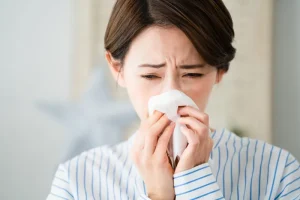 重度の花粉症に苦しむ女性が鼻をかんでいる様子
